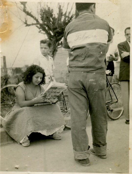 Saturia Rubiano lee un periódico sentada en un andén. 